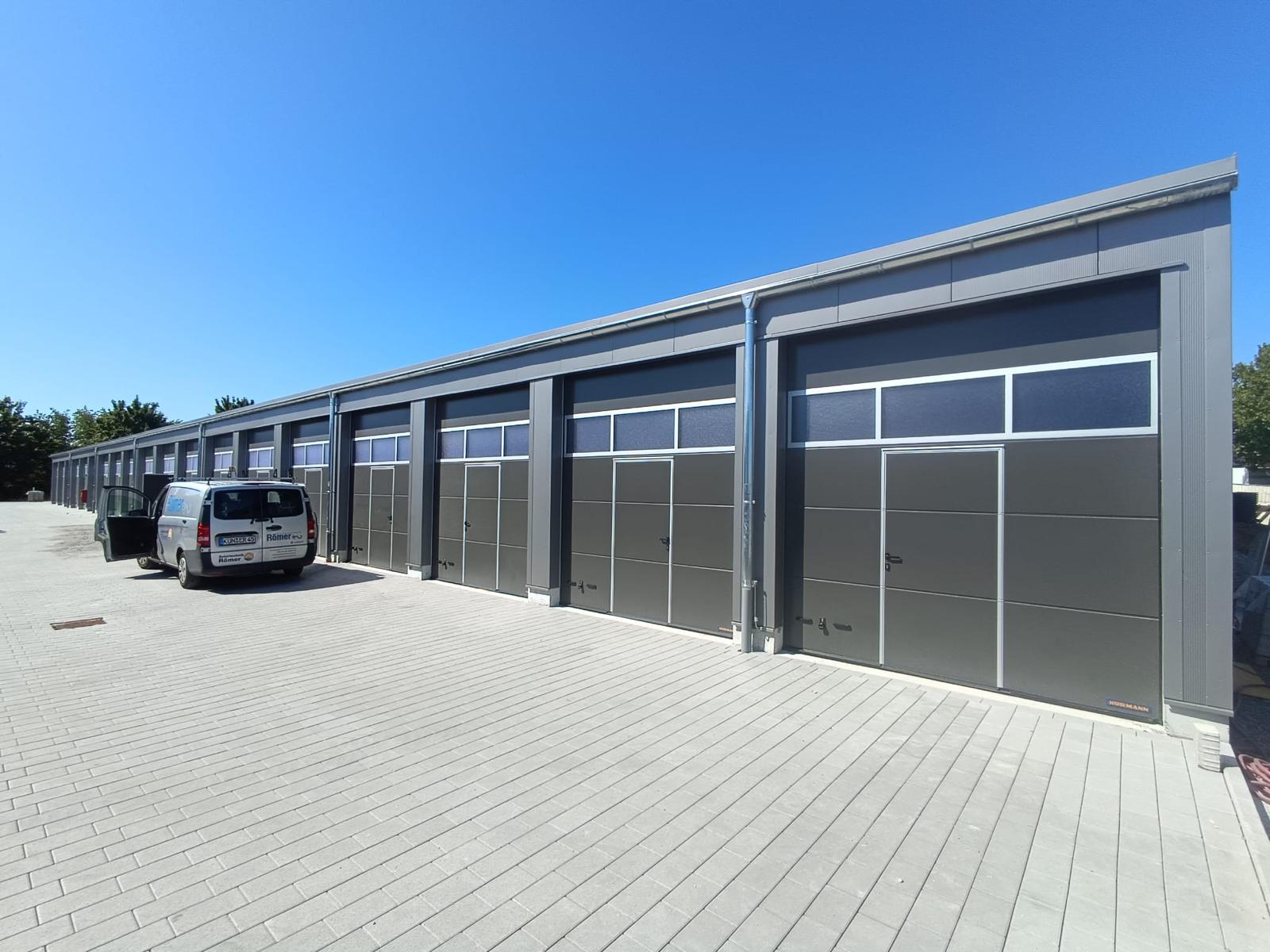 Fertiggestellter Garagenpark mit grauen Sektionaltoren und gepflastertem Vorfahrtsbereich